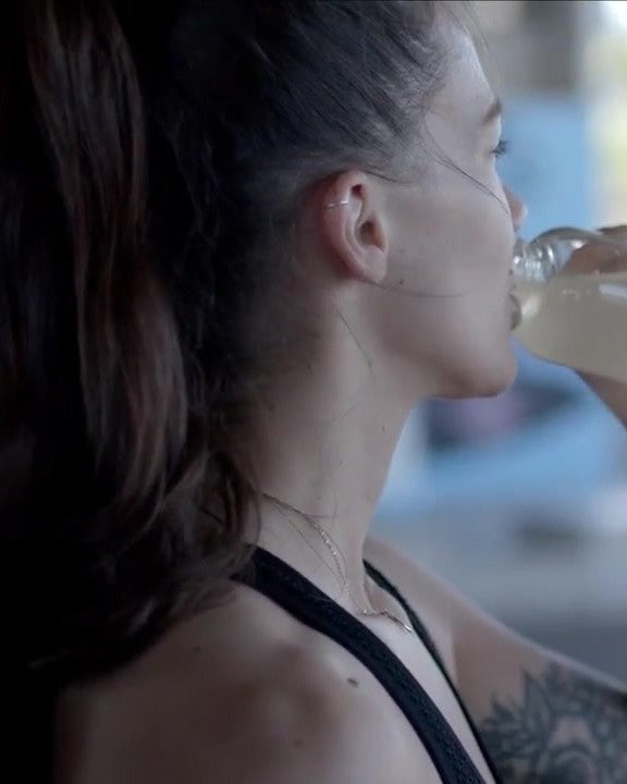 A woman drinking from a Saltivate glass bottle at a skate park