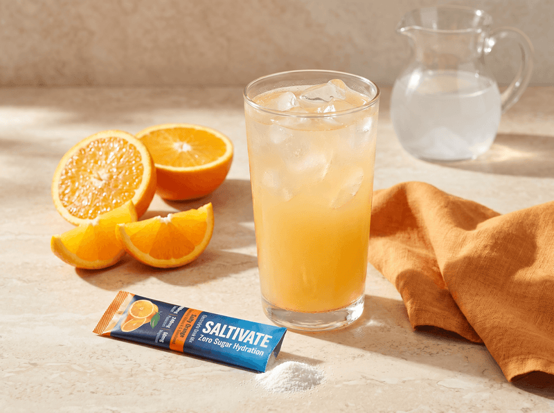 Orange adrenal cocktail over ice with a Saltivate Orange stick packet beside the glass