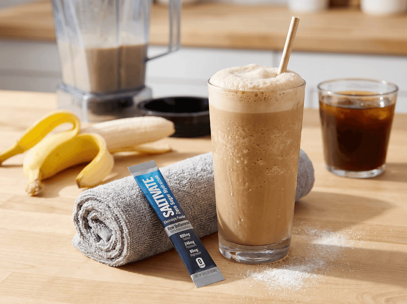 Blended pre-workout iced coffee shake with a banana and a Saltivate stick packet on a gym towel