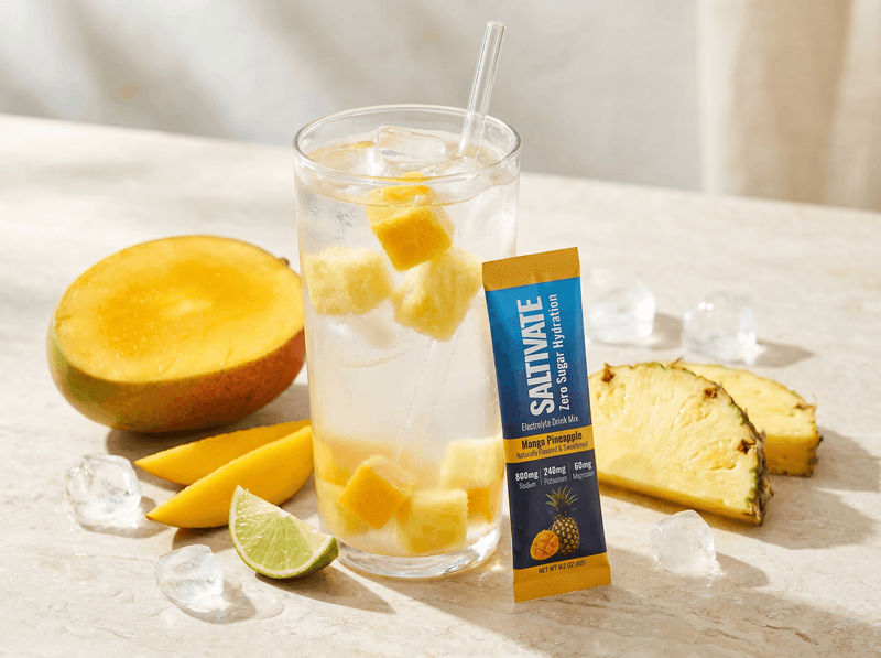 Tall tumbler of tropical fruit water with a Saltivate Mango Pineapple stick packet