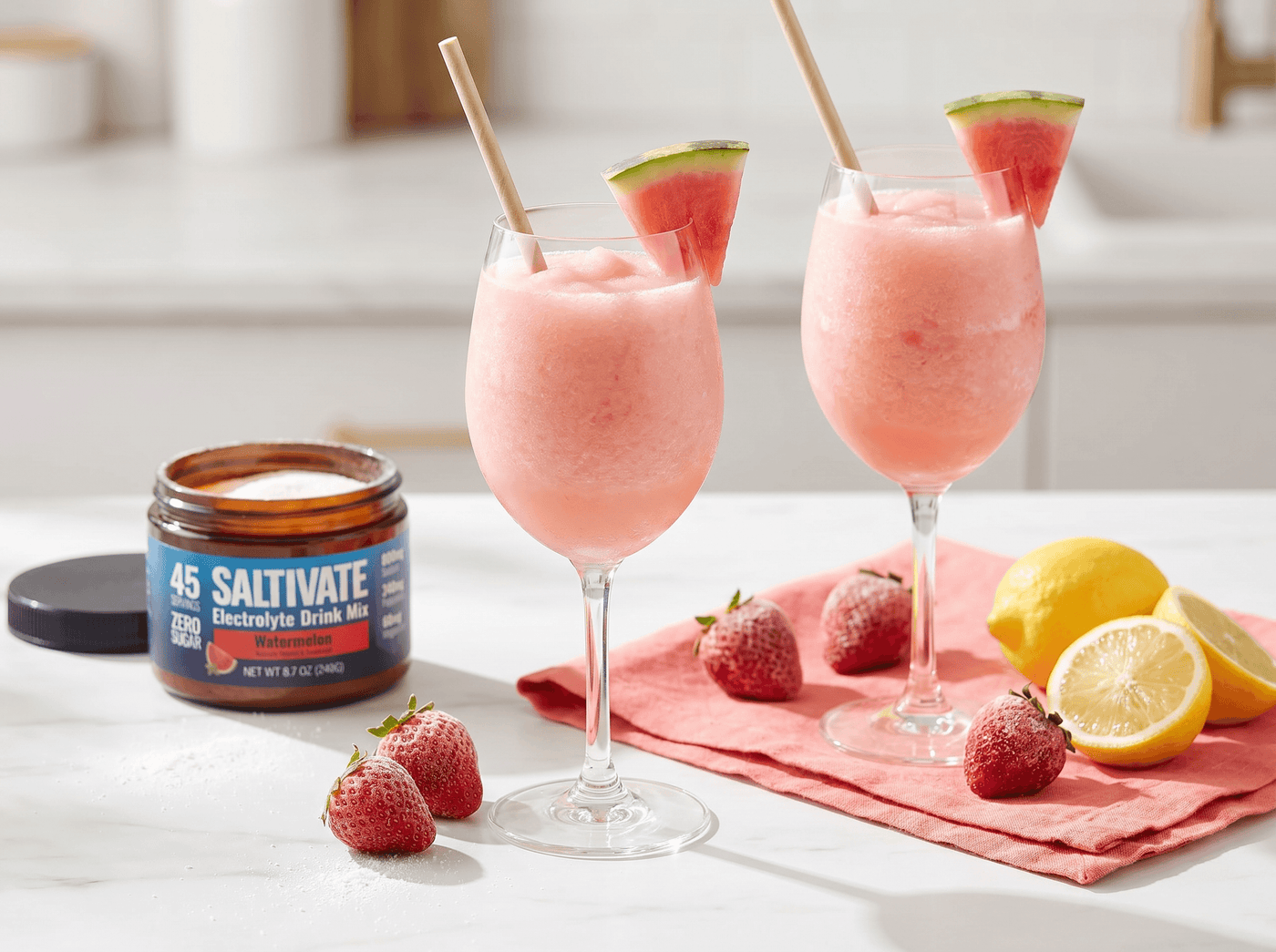 Two glasses of watermelon frose slush with a jar of Saltivate Watermelon