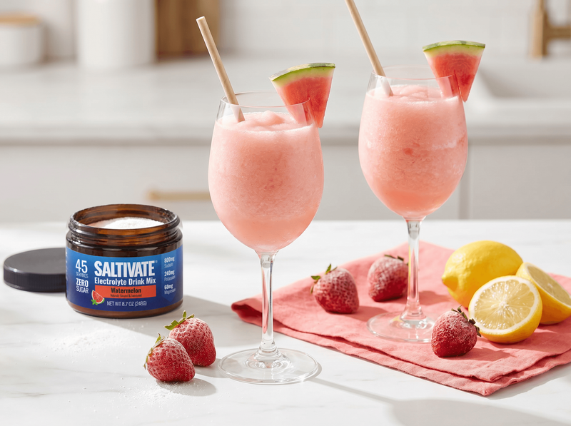 Two glasses of watermelon frose slush with a jar of Saltivate Watermelon