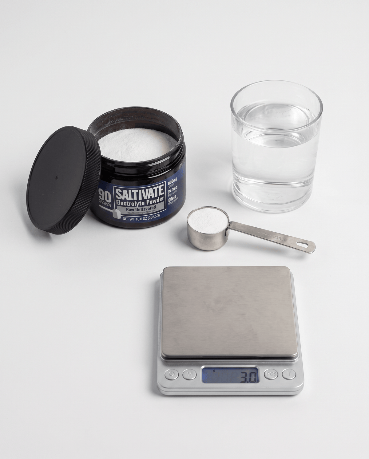 Raw Unflavored jar, level 3 gram scoop, and glass of water on a scale