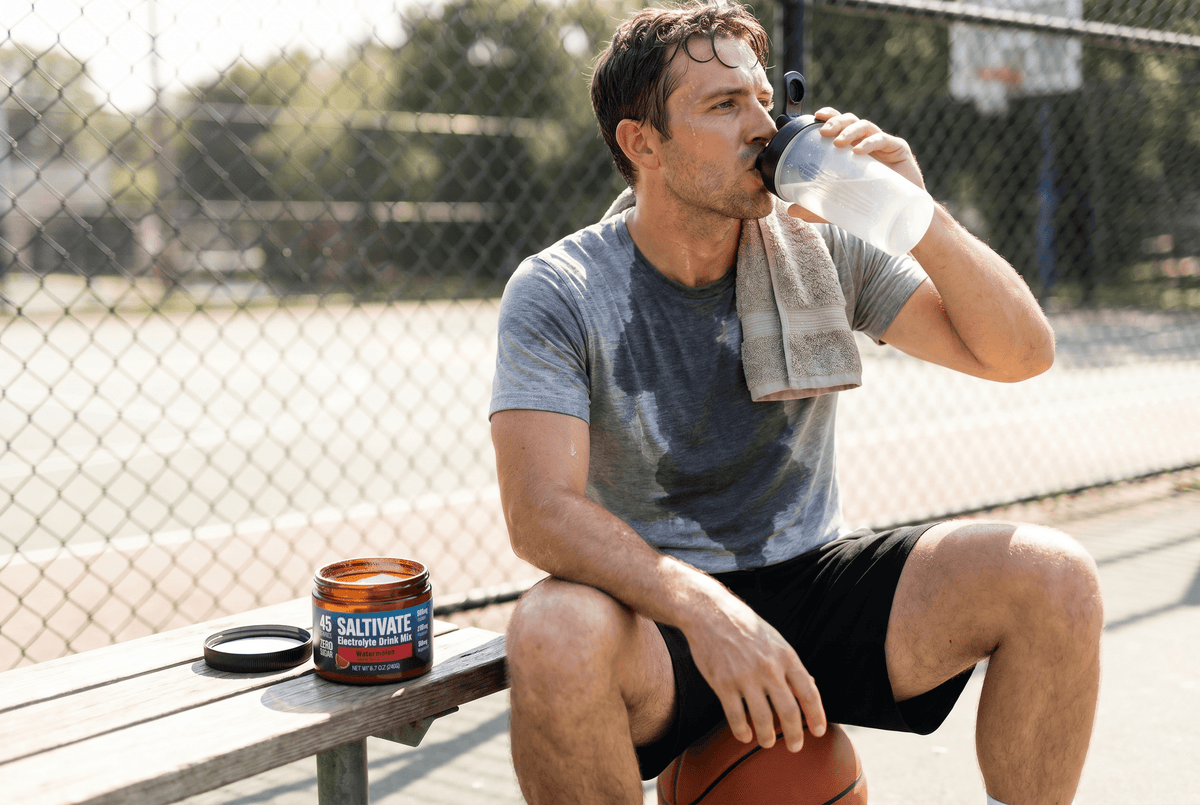 Sweat-soaked player drinking Saltivate from a shaker beside the jar courtside