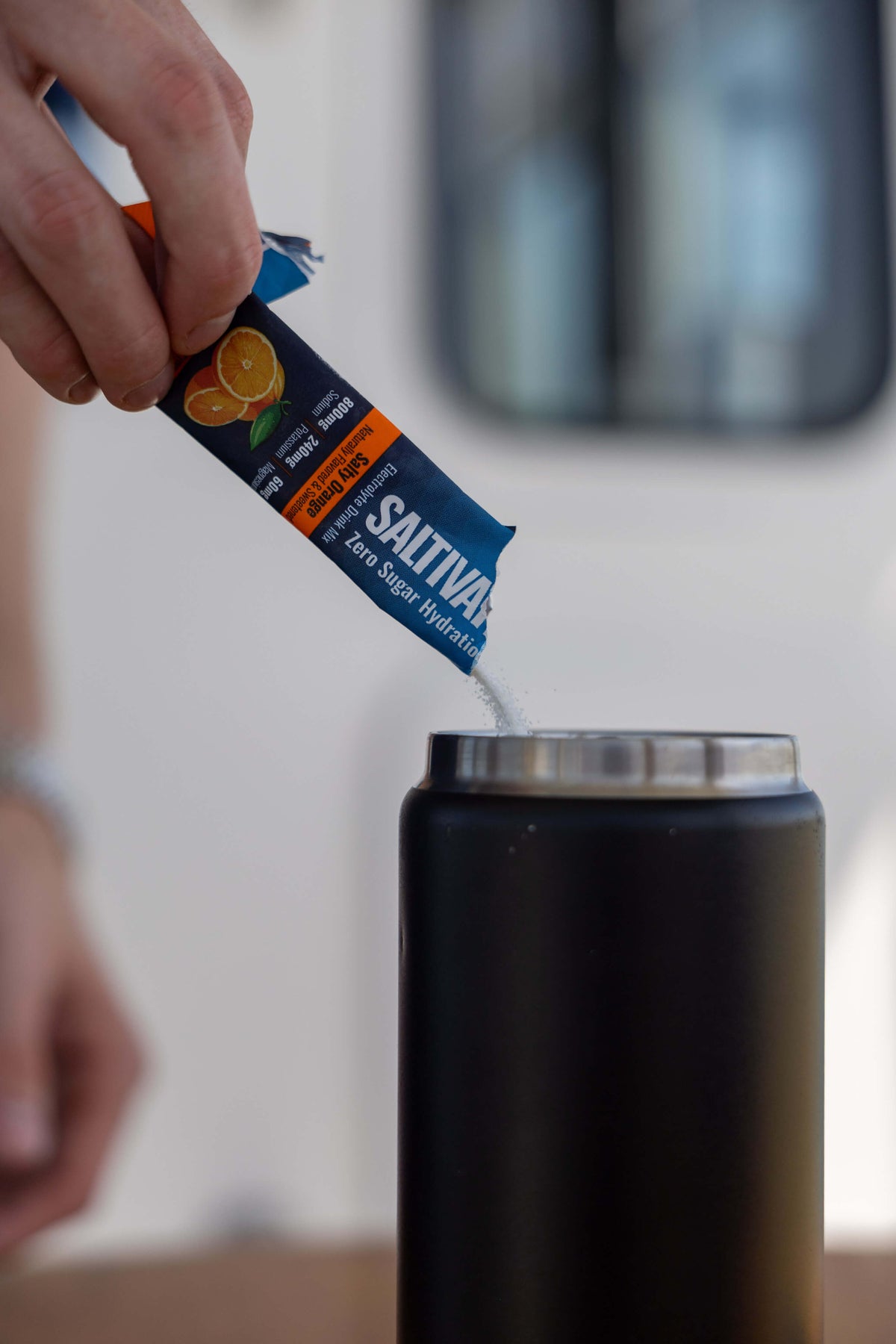 Pouring a Salty Orange electrolyte stick into a water bottle
