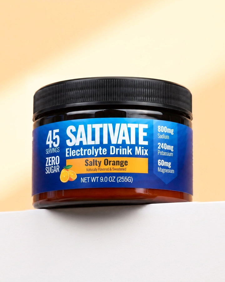 Saltivate Salty Orange jar on a white ledge against a pale peach backdrop