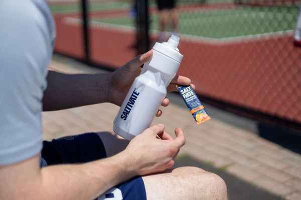 Holding a Saltivate bottle and orange stick pack courtside