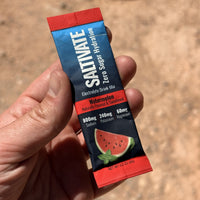 Close-up of a hand holding a Saltivate Watermelon electrolyte stick on a desert trail