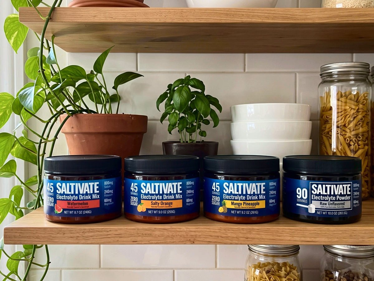 Four Saltivate jars, Watermelon, Salty Orange, Mango Pineapple and Raw Unflavored, in a row on an oak kitchen shelf