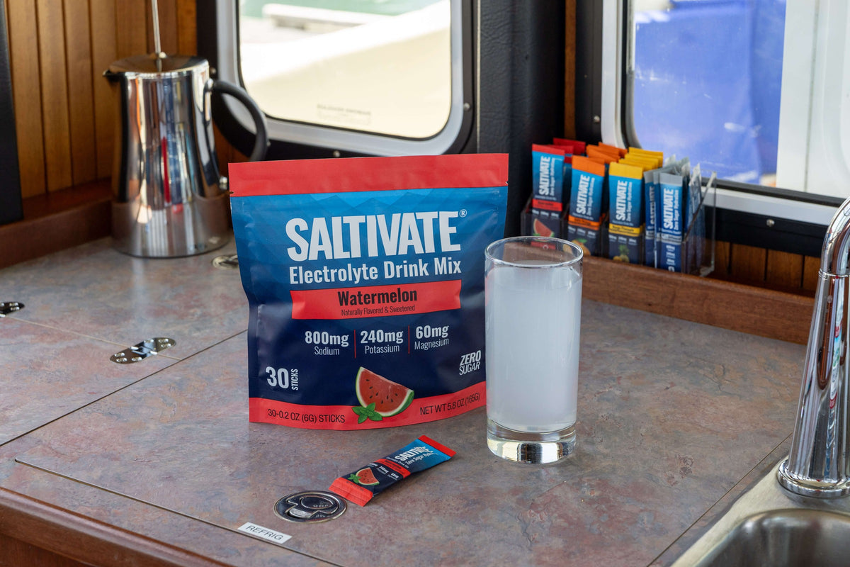 A Saltivate pouch, a packet and a glass of the drink on a counter by a window
