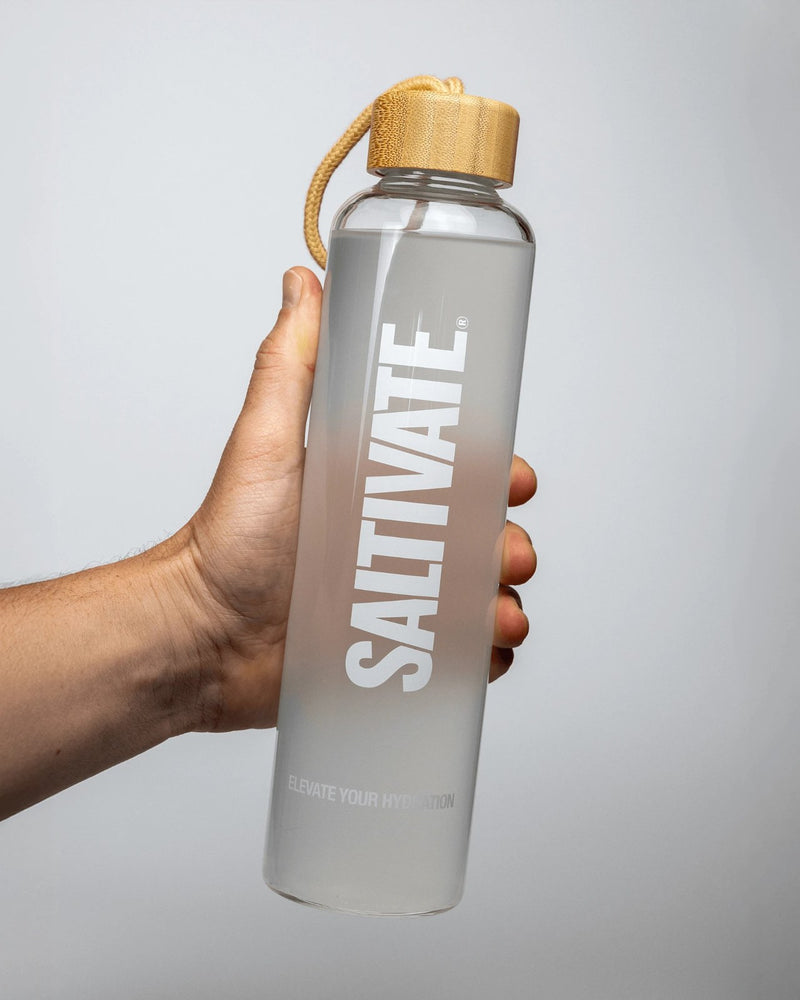 The mixed Saltivate drink in a glass bottle held up in a studio, translucent with a faint white haze