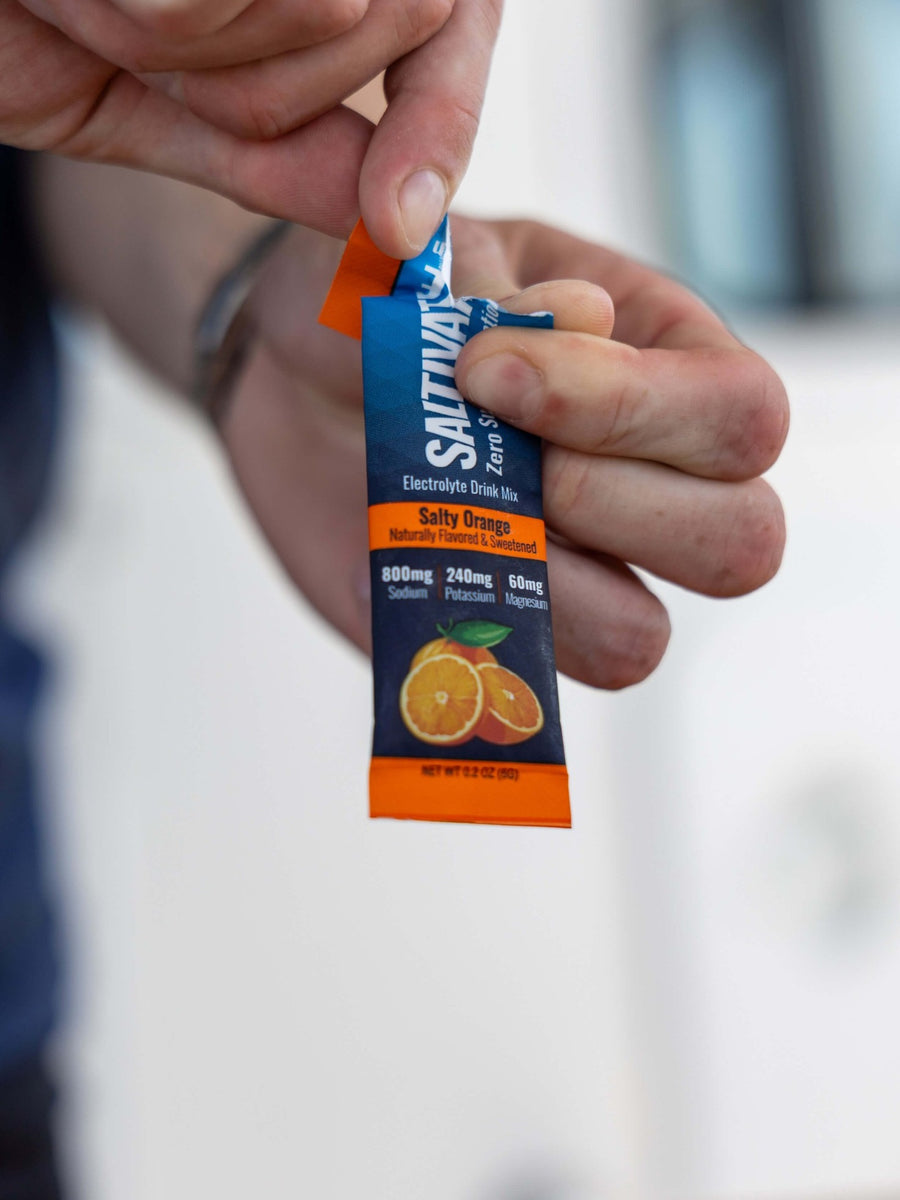 Fingers tearing the top off a Salty Orange packet