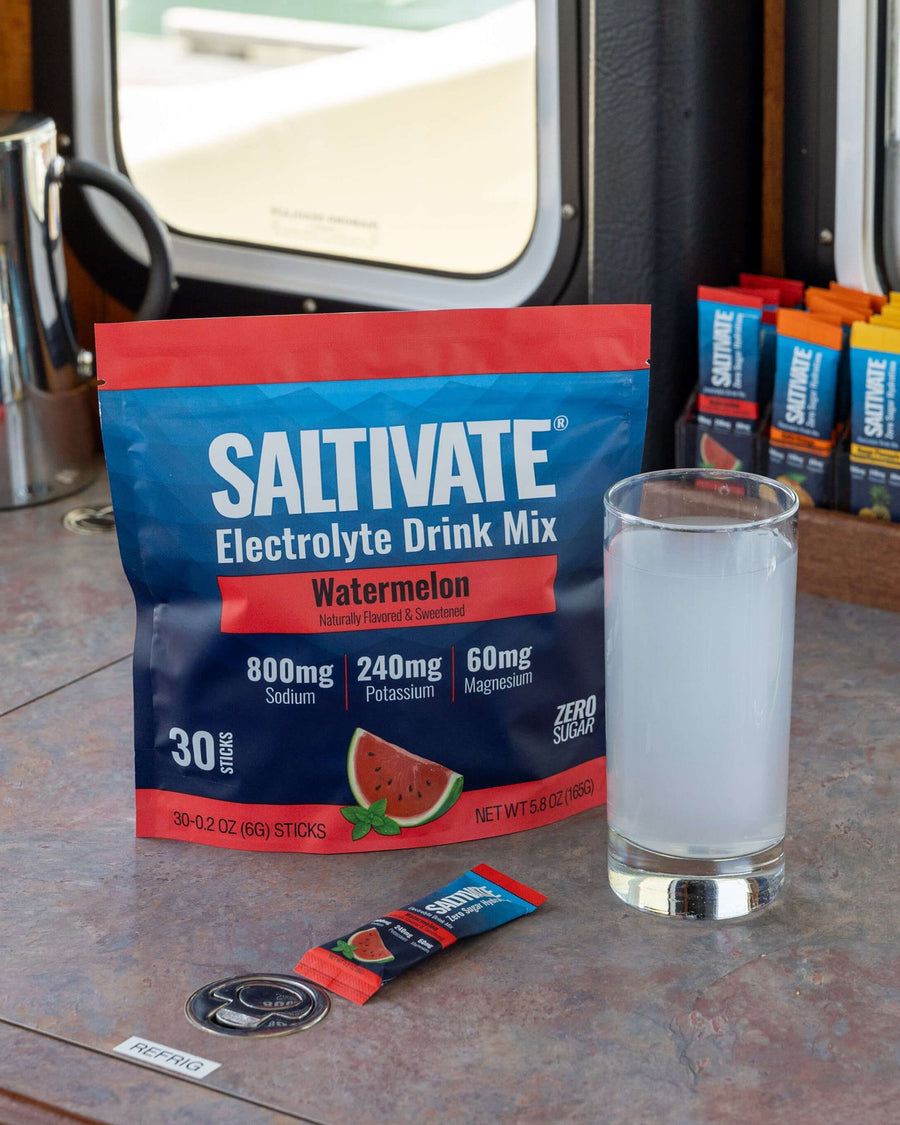 A Saltivate pouch, a packet and a glass of the drink on a counter by a window